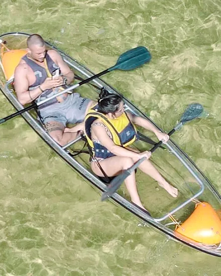Two paddlers in a transparent kayak above the bright lagoon floor