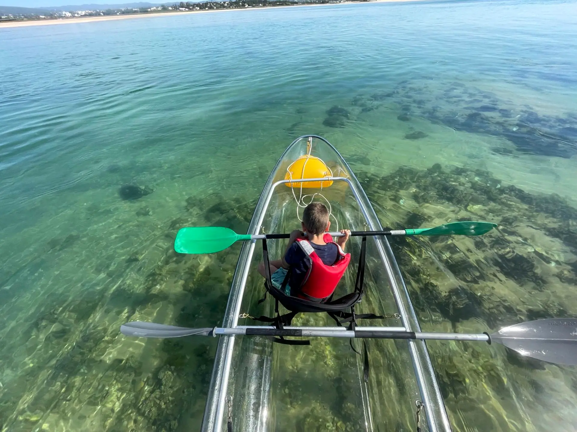 Looking through a transparent kayak hull onto seagrass and sand in the Ria Formosa
