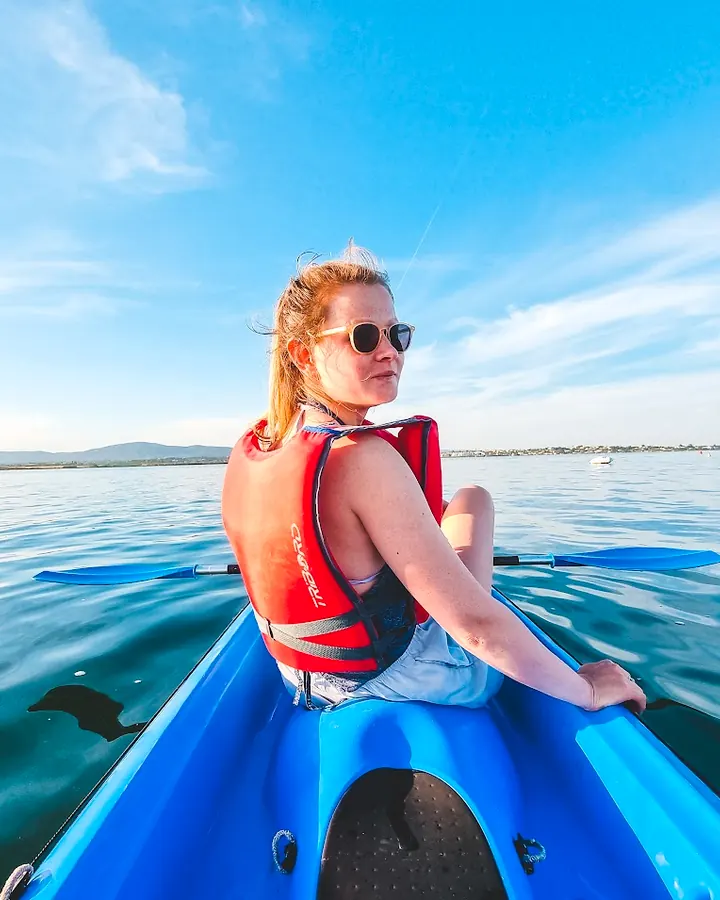 A paddler in a blue kayak on the calm Ria Formosa